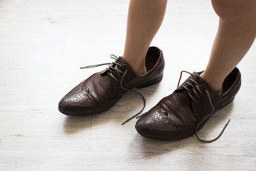 small child, dressed in brown shoes large adult. the child wore dad's shoes