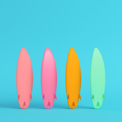 Four colorful surfboards on bright blue background in pastel colors
