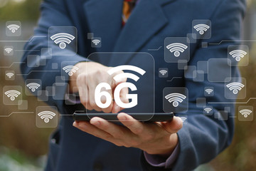 6G networking concept. Businessman using futuristic tablet virtual display, pressing button 6G icon