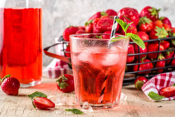 Iced strawberry drink, juice, mojito cocktail or liqueur, with fresh strawberries, light beige concrete background copy space selective focus