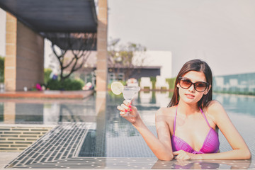 Swimsuit Concept. Beautiful girl wearing pink swimsuit. Beautiful girl in swimwear is relaxing at the swimming pool. Independent living sexy woman at the city center pool.