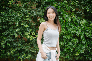 Naklejka na ściany i meble lifestyle fashion portrait of young stylish hipster Asia woman on green leaves background