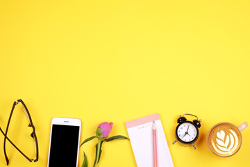 Top view of female worker desktop with laptop, flowers and different office supplies items. Feminine creative design workspace.