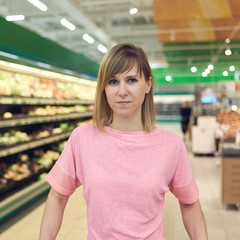 Beautiful young woman shopping for vegetables in produce department of a grocery store supermarket.