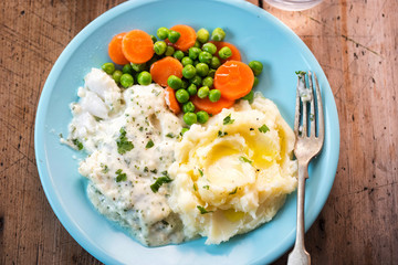 Cod fillet in parsley sauce with mash, peas and carrots. 