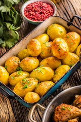 Roasted potatoes with herbs in pan on rustic oak table