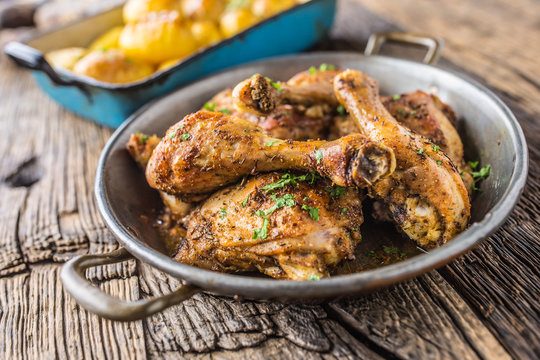 Roasted chicken legs in pan on rustic oak table