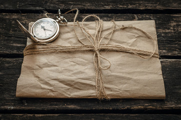 Old vintage letter envelope, feather pen and inkwell on aged wooden table board background. Retro package.