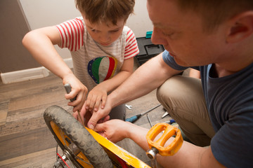 the father and his son repair the bicycle in the home