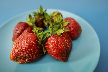 Ripe strawberries on a blue plate.