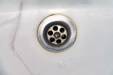 View of the sink, drain and flowing water for background, close-up