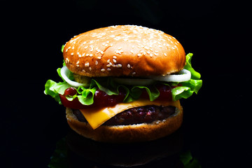 Fresh tasty burger on black background. Tasty and appetizing cheeseburger. Meat burger