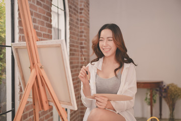 Concept Artist Beautiful girl. Beautiful women are creating art. Beautiful woman is painting happily. Young artist painting in the gallery.