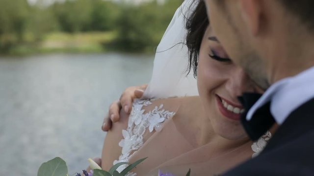 Beautiful wedding couple. Elegant gentle stylish groom and bride near river or lake. Newlywed couple in love. Bride lokking at camera