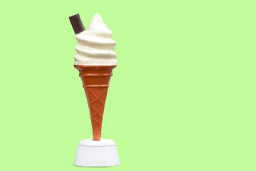 Vintage plastic promotional UK ice cream cone with vanilla whipped ice cream and a chocolate flake with a green background in UK