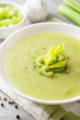 Celery cream soup in white plate on gray stone background