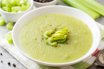 Celery cream soup in white plate on gray stone background