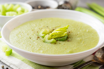 Celery cream soup in white plate on gray stone background