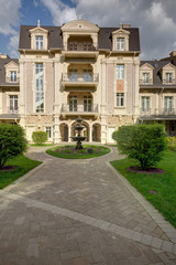 Fototapeta premium The three-storyed house with the fountain and bushes of greens