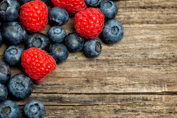 Strawberry, raspberry and blueberries on vintage wooden board background, top view