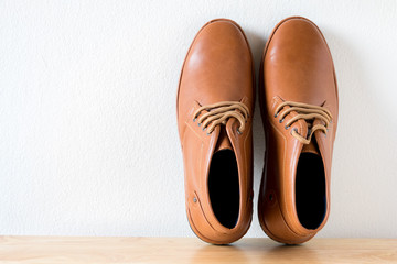 Vintage brown men fashion shoes on the table and white wall