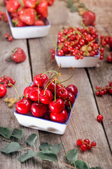 Fresh summer berries - strawberry, cherry and red current in ceramic bowls on the rustic wooden table. Summer healthy diet. Farmer harvest concept. Selective focus, space for text.