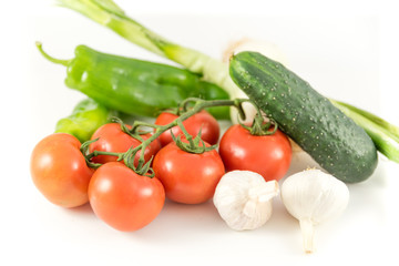 bunch of tomatoes, garlic, cucumbers, peppers and onions on white background