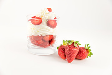 homemade dessert of strawberries with cream in glass cup on white background