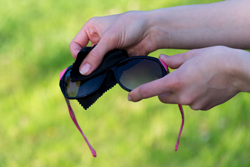 Female hands cleaning sunglasses outdoors