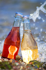 Two bottles of cocktail on beach.
