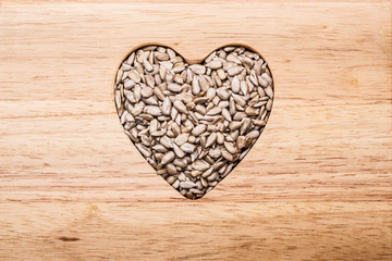 Heart shaped sunflower seeds on wood surface