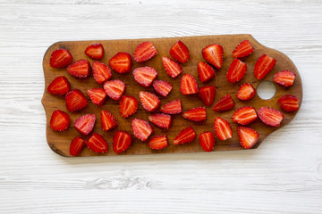 Fresh raw strawberries on wooden board, top view. White wooden background.