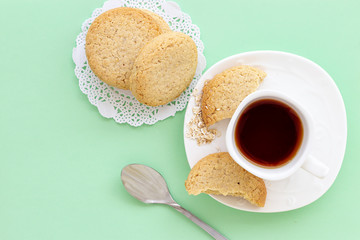 Glutenfree homemade oatmeal cookies cup of tea or coffee espresso on pastel green background. Mint color background. Top view.
