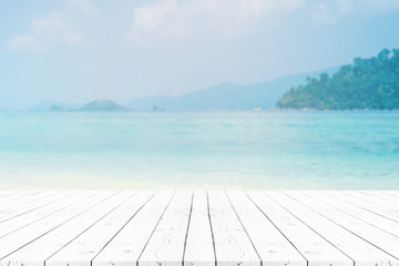 Perspective white pearl wooden table on top over blur sea in sunny day background. Beautiful sea and clouds in Thailand on summer, can be used mock up for montage products display or design layout.