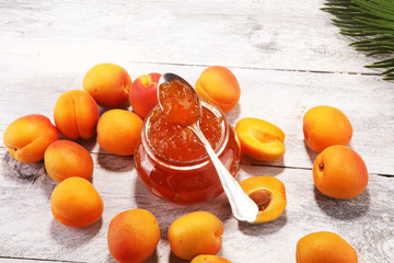 apricot jam and a bunch of fresh apricots on wooden table.