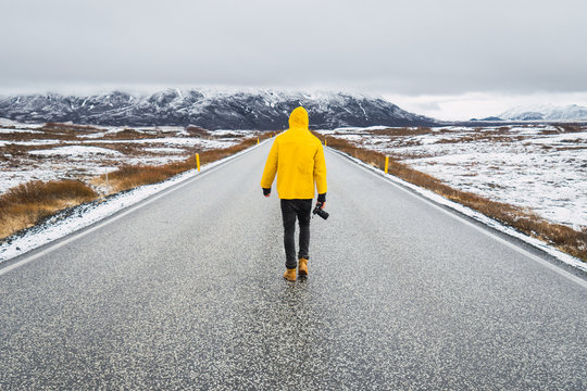 Anonymous photographer waking on snowy road