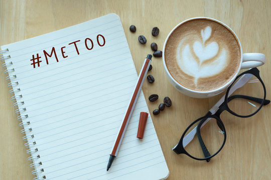 MeToo hashtag on note book with coffee cup, top viwe on wooden pine table background. Flat lay design. As part of anti sexual harassment and assault social media internet campaign protests