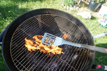 Cutlery for sausages barbecue with a charcoal barbecue in the garden
