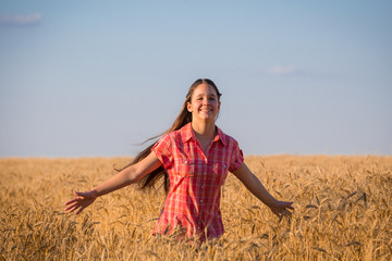 young girl walking on field with ripe wheat