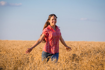 young girl walking on field with ripe wheat