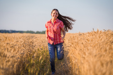 Naklejka na ściany i meble young girl running on field with ripe wheat