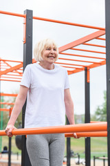 happy senior sportswoman exercising on sports ground