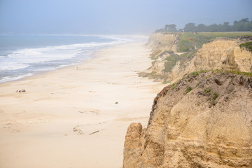 Aerial view of green bluff, beautiful beach and waves in the ocean