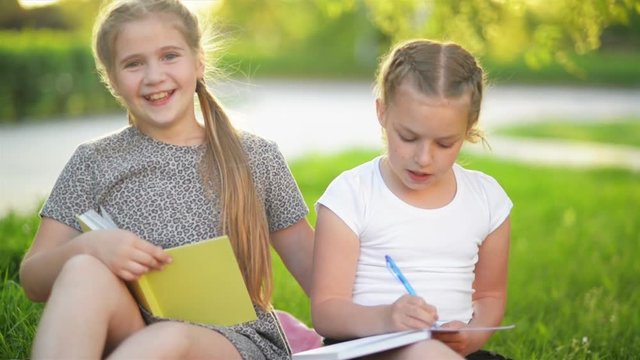 Cutie Girls Doing Homework Together Outdoor. They Are Getting Knowledge Afterschool.