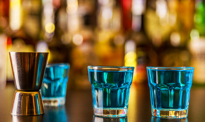 Popular blue drink shot kamikaze on the background of the bar with bottles, a refreshing drink