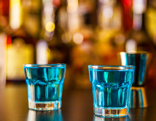 Popular blue drink shot kamikaze on the background of the bar with bottles, a refreshing drink
