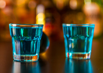 Popular blue drink shot kamikaze on the background of the bar with bottles, a refreshing drink