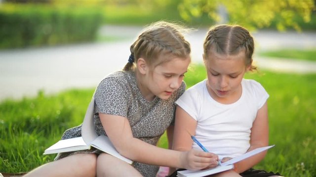Girls Doing Homework in the Summer Garden. They Are Having a Lot of Fun Getting Knowledge.