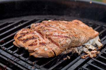 Salmon on the grill freshly seasoned and cut to check readiness