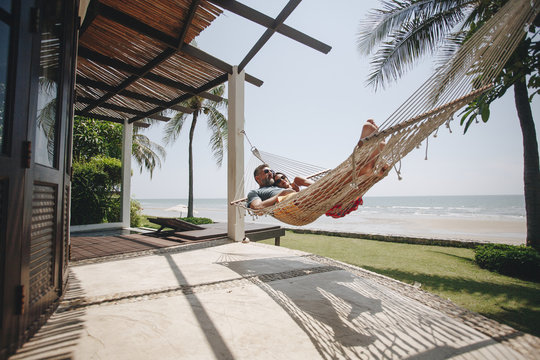 Couple Relaxing In A Hammock By The Beach